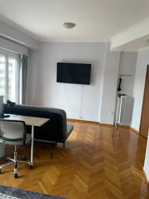 a living room with a table and a tv on the wall at 45 τμ διαμέρισμα in Athens
