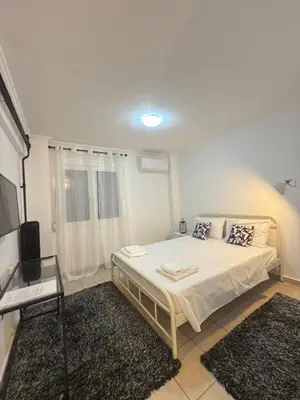 a white bedroom with a bed and a television at New Place Athens in Athens