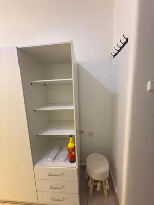 a white cabinet with a stool in a closet at New Place Athens in Athens