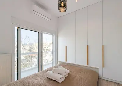 a bedroom with white walls and a bed with towels on it at Acropolis view 2BD top floor next to tram and port in Piraeus