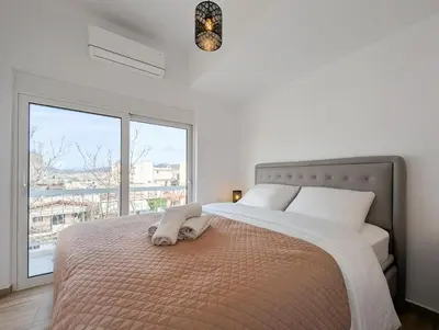 a bedroom with a large bed with a large window at Acropolis view 2BD top floor next to tram and port in Piraeus