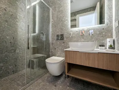 a bathroom with a toilet and a glass shower at Acropolis view 2BD top floor next to tram and port in Piraeus