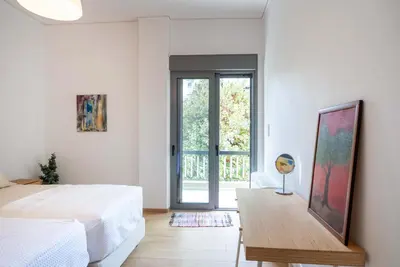 a white bedroom with a bed and a table at Bright Urban Retreat in Athens in Athens