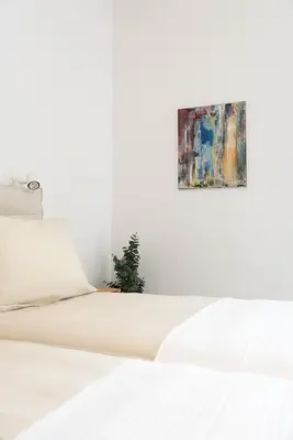 a white bed with a painting on the wall at Bright Urban Retreat in Athens in Athens