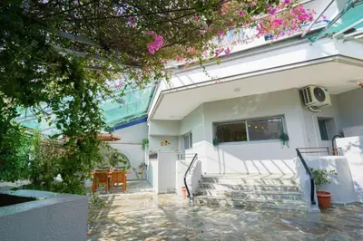 a white house with a table and chairs at Moschato modern cozy apartment with private yard in Piraeus