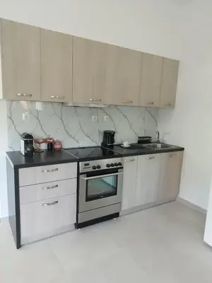 a kitchen with stainless steel appliances and white cabinets at Moschato modern cozy apartment with private yard in Piraeus