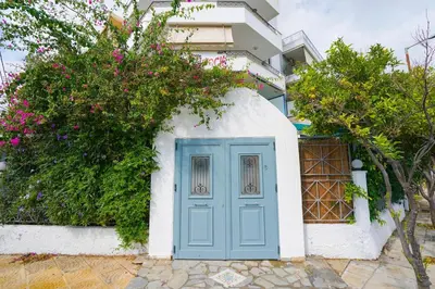 a blue door on a white building with flowers at Moschato modern cozy apartment with private yard in Piraeus
