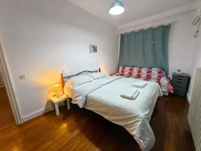 a bedroom with a large white bed with a green curtain at evaxila \u5496\u5561\u5c9b in Glyka Nera