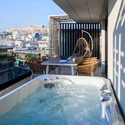 a hot tub on a balcony with a table at Thea Acropolis Suites & Apartments in Athens