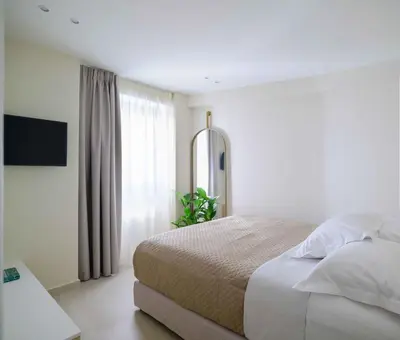a white bedroom with a bed and a window at Thea Acropolis Suites & Apartments in Athens