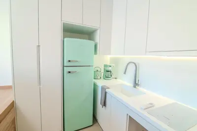 a white kitchen with a refrigerator and a sink at Monastiraki Center Stay in Athens