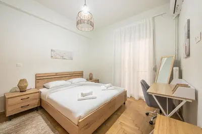 a white bedroom with a bed and a desk and a desk at Zen sunny, Zografou in Athens