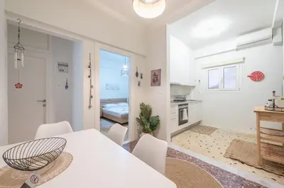 a white dining room with a white table and chairs at Zen sunny, Zografou in Athens