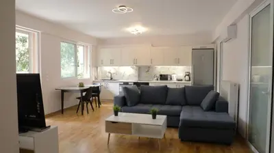 a living room with a blue couch and a kitchen at Luxury 1 Bd Apt with Patio in Neo Psychiko in Athens