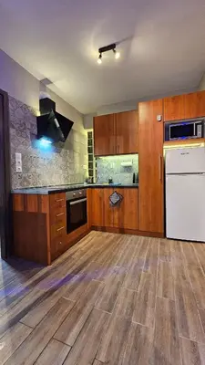 a kitchen with wooden cabinets and a white refrigerator at Μοντέρνο Ημιυπόγειο στουντιο διαμέρισμα στην Αθήνα με αυλή in Athens
