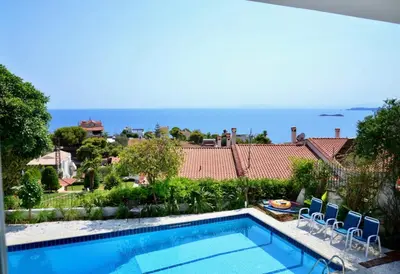 a swimming pool with chairs and the ocean in the background at Art Blue Residence Maisonette in Aghia Marina