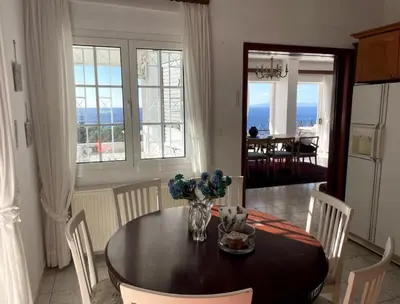 a dining room with a table and chairs with a view of the ocean at Art Blue Residence Maisonette in Aghia Marina
