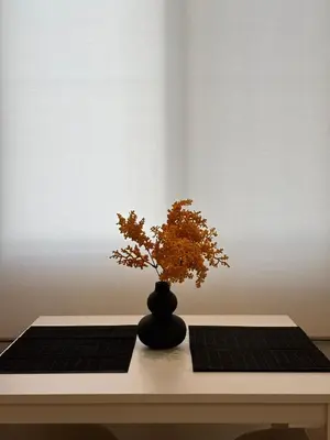 a black vase with a plant sitting on a table at Thymeli Cozy Apartment in Athens