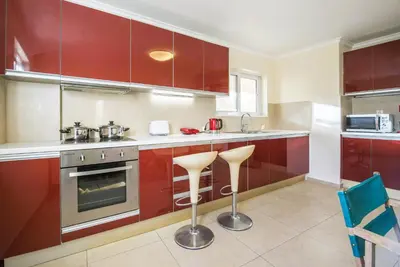 a kitchen with red cabinets and two stools at Elegant Urban Retreat in Psychiko in Athens