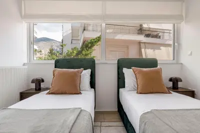 two beds sitting in a room with a window at The Glyfada Getaway 3BR with Balcony by UPSTREET in Athens