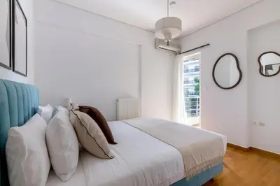 a bedroom with a bed with pillows and a window at The Glyfada Getaway 3BR with Balcony by UPSTREET in Athens