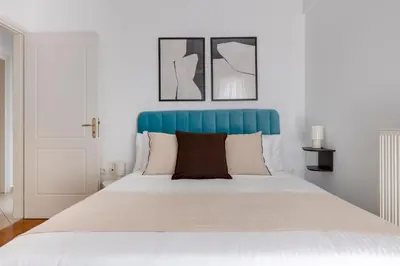 a white bed with a blue headboard in a bedroom at The Glyfada Getaway 3BR with Balcony by UPSTREET in Athens