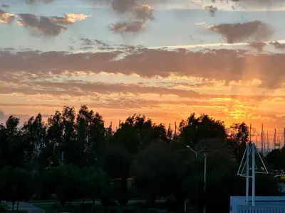 a sunset with trees and clouds in the sky at Elaia Luxury Selections - Aqua Marine in Athens