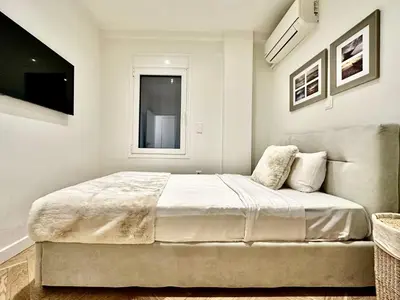a white bedroom with a large bed and a window at Elaia Luxury Selections - Aqua Marine in Athens