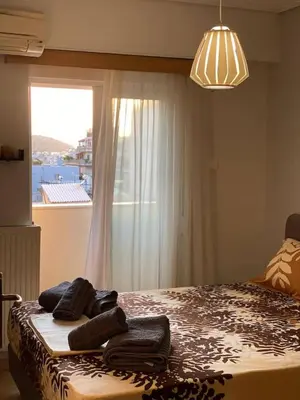 a bedroom with a bed with towels on it with a window at Goudi Athenian 4th floor Apartment in Athens