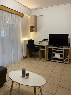 a living room with a desk with a tv and a table at Goudi Athenian 4th floor Apartment in Athens