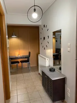 a living room with a table and a clock on the wall at Goudi Athenian 4th floor Apartment in Athens
