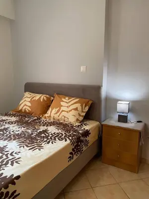 a bedroom with a bed and a nightstand with a lamp at Goudi Athenian 4th floor Apartment in Athens