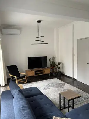a living room with a blue couch and a tv at Apartment with sea view in Piraeus