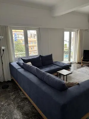 a large blue couch in a living room with windows at Apartment with sea view in Piraeus