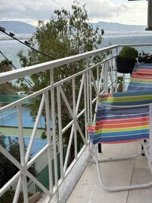 a colorful chair sitting on a balcony overlooking the water at Apartment with sea view in Piraeus