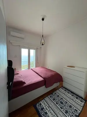 a bedroom with a red bed and a window at Apartment with sea view in Piraeus