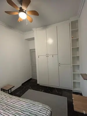 a bedroom with white cabinets and a ceiling fan at Apartment with sea view in Piraeus