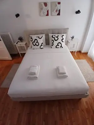 a large white bed in a room with wooden floors at The Cozy Spot Athens in Athens