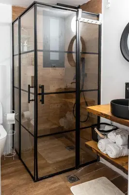 a glass shower in a bathroom with a wooden wall at The Cozy Spot Athens in Athens