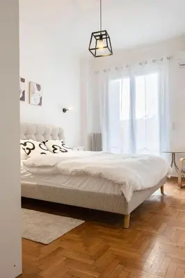 a white bedroom with a large bed and a window at The Cozy Spot Athens in Athens
