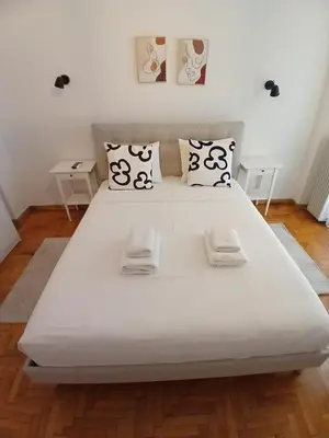 a large white bed in a room with two tables at The Cozy Spot Athens in Athens