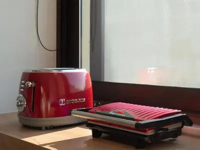 a red toaster sitting on a table next to a window at Artemis Moonlight Suit in Athens