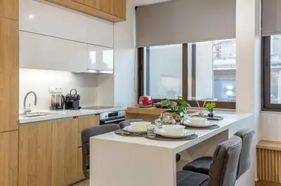 a kitchen with a large white island with chairs at Artemis Moonlight Suit in Athens