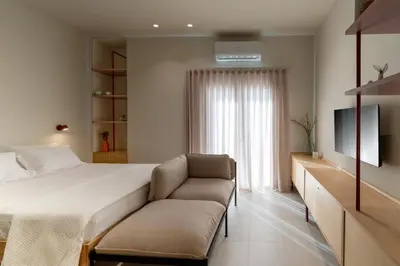 a bedroom with a bed and a couch and a television at MelAngelo Villas A - Modern Studio near Port of Piraeus in Piraeus