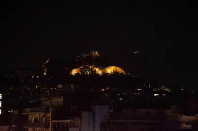 a view of a mountain at night with lights at 180 jacuzzi with Acropolis sunset view in Athens