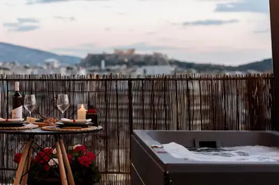 a bath tub with a table with wine glasses and candles at 180 jacuzzi with Acropolis sunset view in Athens