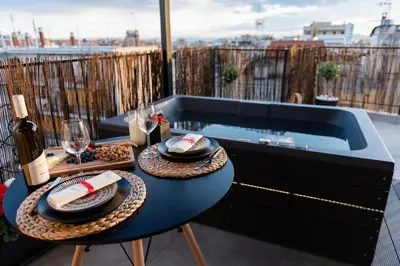 a hot tub on a balcony with a table with wine glasses at 180 jacuzzi with Acropolis sunset view in Athens