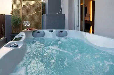 a bath tub filled with blue water in a bathroom at Hot tub with Acropolis view 1 minute from METRO TRAIN in Athens