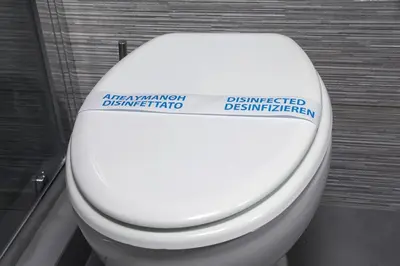 a white toilet with a sign on the lid at Evelyn's cozy house in Athens