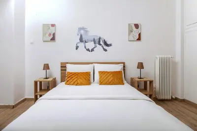 a bedroom with a white bed with two orange pillows at Evelyn's cozy house in Athens